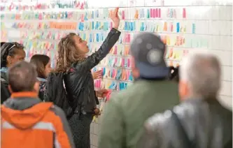  ??  ?? In this file photo, a commuter places a sticky note on the Subway Therapy wall, in New York.