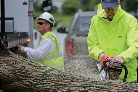  ?? STUART CAHILL / HERALD STAFF (ABOVE); CHRIS CHRISTO / HERALD STAFF (BELOW) ?? DOWNED ... AND OUT: Workers cut a tree that fell on Country Way in Scituate, taking out power lines. Below, a Jeep sits in high water at the Providence and Worcester Intermodal Yard in Worcester.