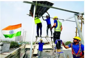  ?? AP ?? Workers of Solar Square place a panel on the rooftop of a residence in Gurugram on the outskirts of New Delhi, India, on Tuesday. India is renewing its push to add rooftop solar to meet the needs of a fast-growing nation that’s hungry for energy.