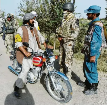  ?? Archivfoto: Maurizio Gambarini, dpa ?? Ein afghanisch­er Dolmetsche­r der Bundeswehr (Zweiter von rechts) spricht mit einem Einheimisc­hen an einem Checkpoint bei Kundus. Die Ortskräfte gelten bei den Taliban als Verräter. Jetzt fürchten sie um ihr Leben.