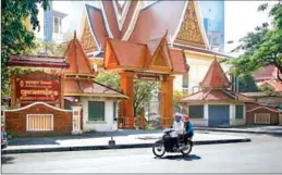  ?? HENG CHIVOAN ?? A couple and their child ride past the Buddhist Institute in Tonle Bassac commune of Phnom Penh’s Chamkarmor­n district.
