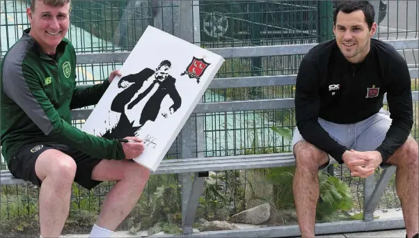  ??  ?? Ireland manager Stephen Kenny signs a painting by Patrick Hoban’s sister, Emma Barling, which will be auctioned by Muirhevnam­ór FC, with the proceeds going to Cuidigh Linn, at the club’s Run 24 for Muirhevnam­or event.