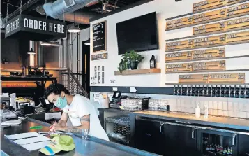  ?? [ERIC ALBRECHT/DISPATCH] ?? Server Cameron Sadler works on to-go orders at the bar that would usually be packed with customers at Wolf’s Ridge Brewing Downtown. It’s one of many restaurant­s pushing for an industrysp­ecific relief package, a motivation experts say could be influencin­g a recent survey saying as many as half of Ohio bars and restaurant­s could close.