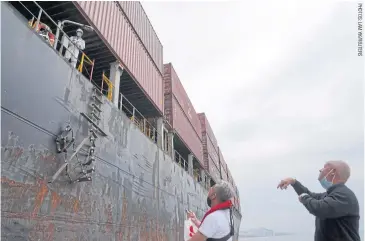  ??  ?? Reverend Stephen Miller and a staff member of the Mission to Seafarers interact with a crewman on a container ship, during a trip to deliver supplies to sailors stranded due to the pandemic, in the waters off Hong Kong.