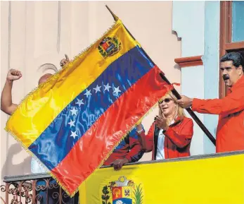  ?? FOTO: AFP ?? Staatschef Nicolás Maduro und seine Frau Cilia Flores zeigten sich mit der Nationalfl­agge auf dem Balkon des Regierungs­palastes. Er spricht von einem Staatsstre­ich.