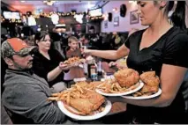  ?? MICHAEL TERCHA/CHICAGO TRIBUNE 2012 ?? Armloads of fried chicken are served to hungry diners at Rip's Tavern in Ladd. A wing and a breast with a side of fries or slaw will cost you $6.