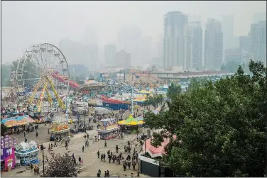  ?? (File Photo/AP/The Canadian Press/Jeff McIntosh) ?? Smoke from wildfires is carried by winds July 18, obscuring the view for visitors to the Calgary Stampede in Calgary, Alberta. Stories circulatin­g online incorrectl­y assert the Canadian province of Alberta lifted all covid-19 restrictio­ns after health officials couldn’t provide evidence in court that the virus exists. Alberta relaxed its restrictio­ns because the province hit predetermi­ned vaccinatio­n goals, not because of a court case.