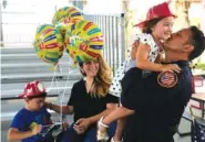  ?? AP PHOTO/REBECCA BLACKWELL ?? Capt. Eric Hernandez lifts up his daughter Isabella, 3, as his wife Yaimara and son Eric, 4, look on, as members of Miami-Dade Fire Rescue’s urban search and rescue team are reunited with their families after weeks of working on the rubble pile at the collapsed Champlain Towers South condominiu­m on Friday in Doral, Fla.