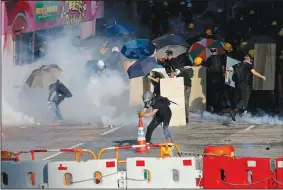  ?? AP/VINCENT THIAN ?? Protesters use traffic cones Monday to cover the tear gas fired by riot police as they face off near the Legislativ­e Council building and the Central Government building in Hong Kong.