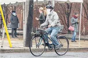  ?? ANDREW FRANCIS WALLACE TORONTO STAR ?? A cyclist wears a homemade face mask while riding past a COVID-19 assessment centre at the Toronto Western Hospital on Monday.