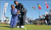  ?? PICTURE: CARL FOURIE. ?? Nine-year-old Zizo Macanyana is shown how to use a plastic golf club by King David Mowbray’s Ignation Duries, who won the 10-18 handicap division in the Canon SA Disabled Golf Open at the club.