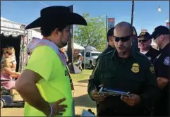  ?? The Associated Press ?? RECRUITMEN­T EFFORT: A U.S. Border Patrol agent gives informatio­n about working for the agency to 24-year-old Ric Kindle, of the Phoenix area, on April 6 at the Country Thunder Music Festival in Florence, Ariz. U.S. Customs and Border Protection, the...