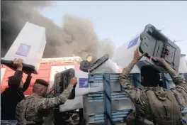  ?? PICTURE: REUTERS ?? Security forces carry ballot boxes as smoke rises from a storage site in Baghdad, housing the boxes from Iraq’s May parliament­ary election, Iraq, yesterday.