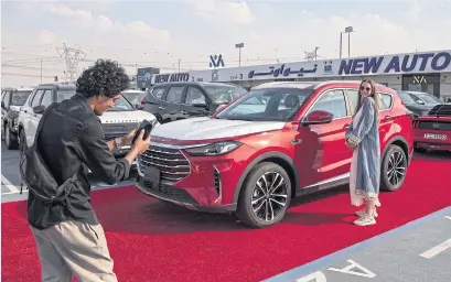  ?? ?? A Russian-speaking sales agent poses for social media content at one of the dealership­s in the car market on the outskirts of Dubai.