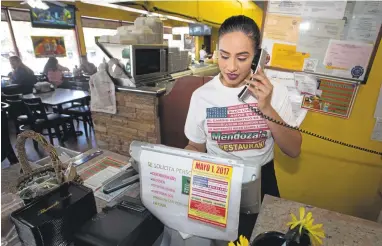  ?? PATRICK TEHAN/STAFF ?? Veronica Novoa takes a phone order Thursday at Mendoza’s Restaurant in San Jose. Mendoza’s is one of several restaurant­s in the South Bay expected to shut down Monday so workers can participat­e in May Day demonstrat­ions.