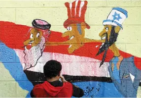  ?? (Khaled Abdullah/Reuters) ?? A PRO-HOUTHI ACTIVIST touches up graffiti condemning Saudi Arabia, the US and Israel on the wall of Riyadh’s embassy in Sanaa, Yemen, on Sunday.