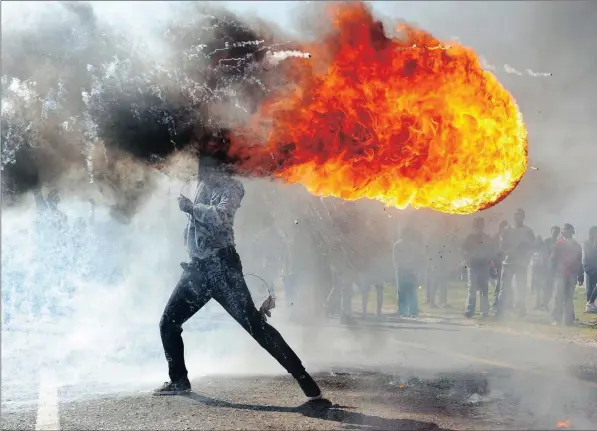  ??  ?? FIERY FRUSTRATIO­N: A young protester swings a tyre in Ou Kaapse Weg in Grabouw, Cape Town, during service delivery protests.