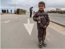  ?? AFP ?? Above, a child walks on a coastal road after being ordered to leave the area near Al Shifa Hospital yesterday; right, a woman sits with an injured boy after an Israeli strike on Gaza city