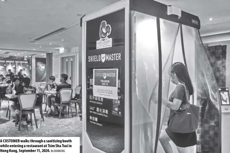  ?? BLOOMBERG ?? A CUSTOMER walks through a sanitizing booth while entering a restaurant at Tsim Sha Tsui in Hong Kong, September 11, 2020.