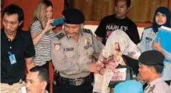  ??  ?? Corby (right) is escorted by police after reporting to a parole office in Denpasar, Bali, on Saturday before her deportatio­n to Australia.