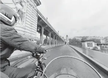  ?? ANNA HARTLEY For The Washington Post ?? The writer and her guide cross the Bir-Hakeim bridge in Paris on a cloudy day via Royal Enfield motorcycle and Watsonian sidecar.