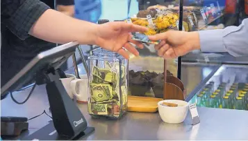  ?? ANNIE RICE/ASSOCIATED PRESS ?? A customer hands a credit card to a cashier at a coffee shop in Chicago. For many small and midsized businesses, how well they’re doing is measured by cash flow.