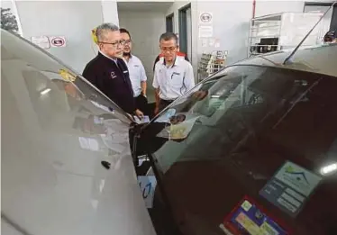  ??  ?? Puspakom chief executive officer Shukor Ismail (left) observing a vehicle being inspected at Puspakom in Petaling Jaya. FILE PIC