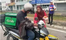 ?? ?? Musliati handing over an iftar food package to a food delivery driver.