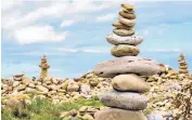  ??  ?? Towers of pink and yellow stones at Holy Island, Northumber­land. Below, a competitor in the European Stone-stacking Championsh­ips tin Dunbar, East Lothian