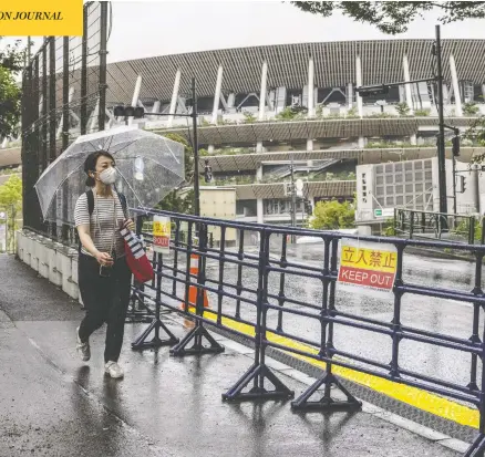  ?? CARL COURT / GETTY IMAGES ?? A woman walks alongside a security fence surroundin­g the Olympic Stadium in Tokyo on Thursday. Japanese Prime Minister Yoshihide Suga
has announced a fourth state of emergency for Tokyo which will run throughout the Olympic Games and remain in place until August 22.