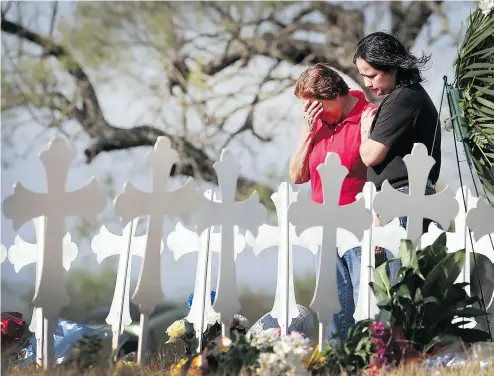  ?? SCOTT OLSON / GETTY IMAGES ?? Maria Durand, left, and her daughter Lupita Alcoces visit a memorial Tuesday where 26 crosses stand to honour the 26 victims killed in a mass shooting at the First Baptist Church of Sutherland Springs, Texas. Durand, who helps to teach Bible study at...