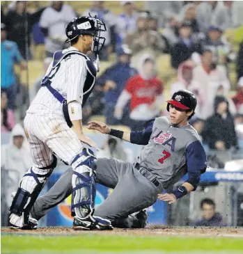  ?? CHRIS CARLSON/ THE ASSOCIATED PRESS ?? Christian Yelich of the U.S. slides past Japan catcher Seiji Kobayashi during the World Baseball Classic in L.A. on Tuesday. The U.S. won 2-1 and will face Puerto Rico in today’s final.