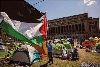  ?? Photos by Yuki Iwamura/Associated Press ?? A protester holds a Palestinia­n flag on Friday at a camp at Columbia University in New York. Student negotiator­s for the camp said the university has not met their demand for divestment.