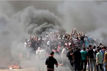  ?? — AFP photo ?? Palestinia­n demonstrat­ors burn tyres near the Gaza-Israel border, east of Gaza City, ahead of the inaugurati­on of the US embassy in Jerusalem.