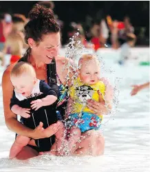  ?? DARREN MAKOWICHUK ?? Mom Allison Ashkin splashes with six-month-old twins Atticus and Arlee at the Bowness Park wading pool.