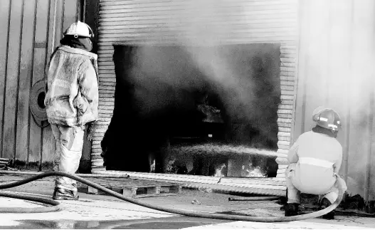  ?? KENYON HEMANS ?? Firefighte­rs work to extinguish the massive fire at a warehouse owned by Singer at 2 Ashenheim Road in St Andrew early yesterday morning.