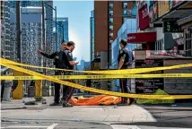  ?? PHOTO: AP ?? Police officers cordon off the scene after a van mounted a sidewalk and ploughed through a crowd of pedestrian­s in Toronto, killing 10 people.