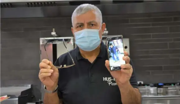 ?? FOTO KRISTIN MATTHYSSEN ?? Ahmet Özer met zijn herstelde bril in pizzeria Hus-Hak 2. Op zijn gsm toont hij een beeld van de bewakingsc­amera.