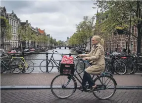  ?? AFP ?? A woman cycles in Amsterdam, one of the few cities in the world that has lowered its obesity rate