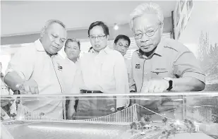  ??  ?? BERSEMANGA­T: Abang Johari (tengah) melihat replika seni bina Jambatan Gantung Satok.
