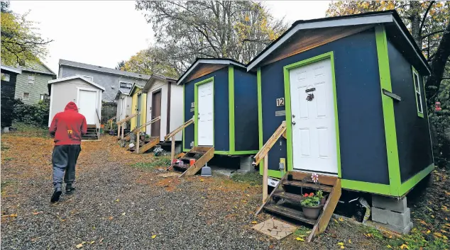  ?? ELAINE THOMPSON THE ASSOCIATED PRESS ?? ABOVE: A resident walks past a row of tiny houses at a homeless encampment in Seattle earlier this month. Tiny homes could be the solution to all kinds of housing needs, but developers in cities across the country have met resistance.