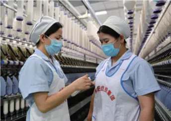  ??  ?? He Fei (left), a deputy to the NPC and a textile worker, interacts with a colleague in her workshop in Xianyang, Shaanxi Province in northwest China, on May 13