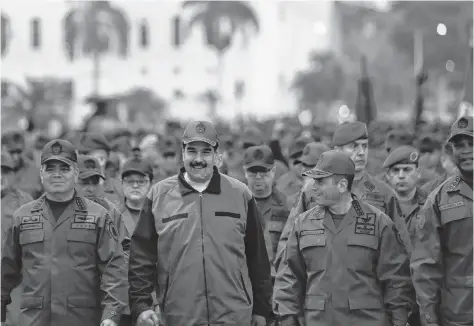  ?? HANDOUT REUTERS ?? Venezuela’s President Nicolas Maduro smiles as he walks next to Venezuela’s defence minister Vladimir Padrino Lopez and Remigio Ceballos, strategic operationa­l commander of the Bolivarian National Armed Forces, during a ceremony at a military base in Caracas, Venezuela on Thursday. •