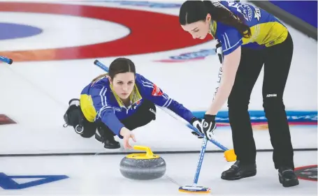  ?? JEFF MCINTOSH/THE CANADIAN PRESS ?? Team Alberta skip Laura Walker, left, fires a rock against Team Canada as second Taylor Mcdonald sweeps during the late draw on Wednesday at the Scotties Tournament of Hearts in Calgary. Walker's crew fell 4-3 to the reigning champions.