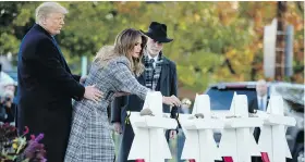  ??  ?? U.S. President Donald Trump and Tree of Life Rabbi Jeffrey Myers look on Tuesday as first lady Melania Trump places a white flower at a memorial for the victims.