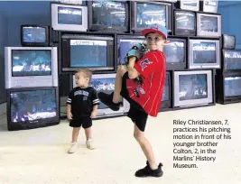  ?? ?? Riley Christians­en, 7, practices his pitching motion in front of his younger brother Colton, 2, in the Marlins’ History Museum.