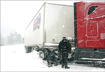  ?? ?? Chains are installed on a big rig’s tires during a storm Saturday in Truckee. A powerful blizzard howled through the Sierra Nevada as the biggest storm of the season shut down a long stretch of Interstate 80 in California and gusty winds and heavy rain hit lower elevations, leaving tens of thousands of homes without power.