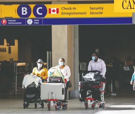  ?? JEFF MCINTOSH / THE CANADIAN PRESS FILES ?? Passengers wear masks at Calgary's airport. It might be up to you to find out if anyone infected with COVID shared your flight, writes John Ivison.