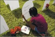  ?? LYNNE SLADKY — THE ASSOCIATED PRESS ?? Kyla Harris, 10, writes a tribute to her grandmothe­r, Patsy Gilreath Moore, who died at age 79 of COVID-19, at a symbolic cemetery last month of Miami. Thursday, there were over 3,000 American deaths.