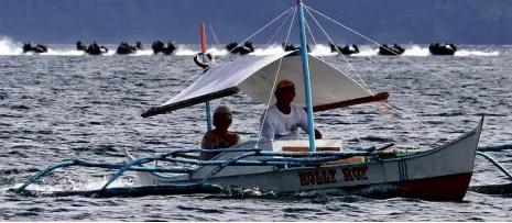  ?? RAFFY LERMA ?? FISHERMEN on a banca pass US and Philippine Marines holding military exercises aboard rubber boats in Ulugan Bay, Palawan province, as part of the Balikatan exercises that ended on Friday.